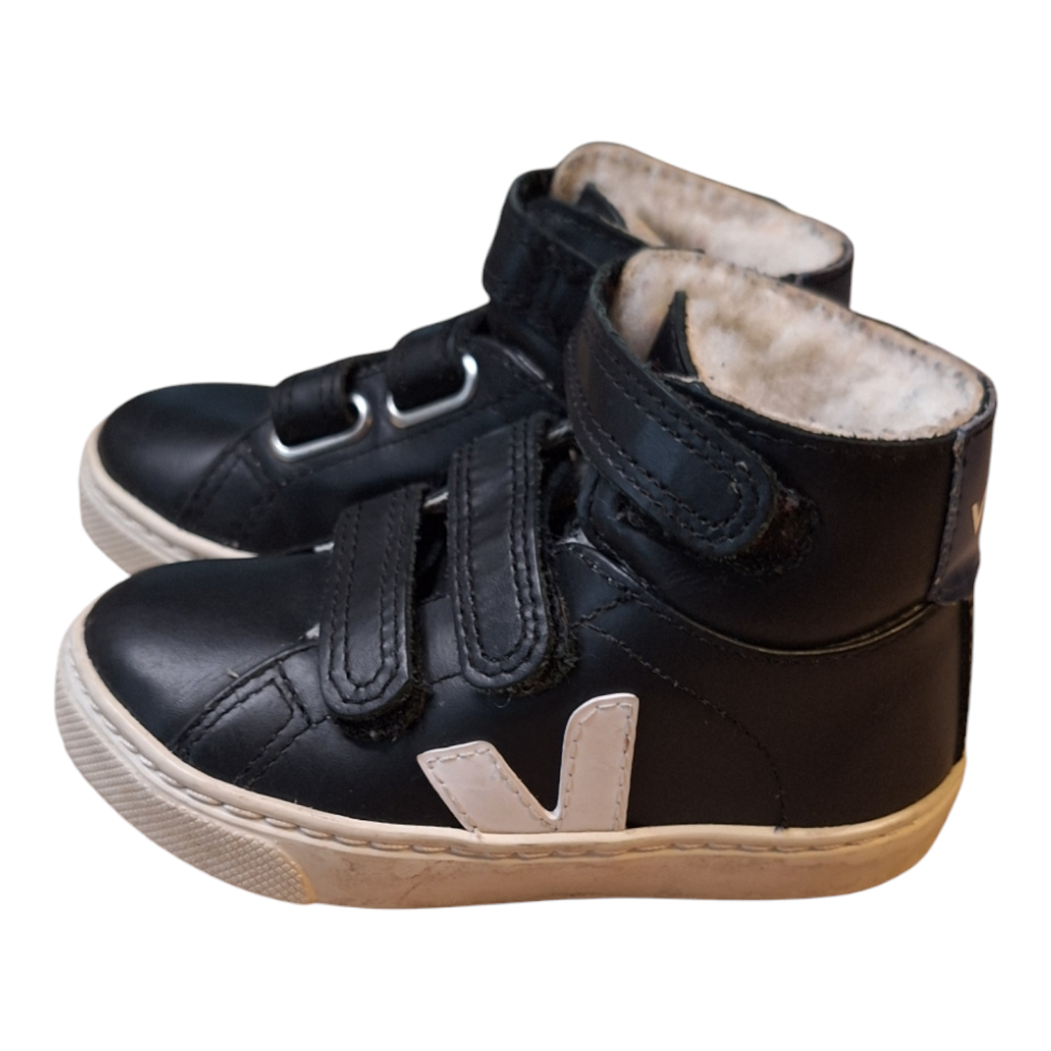 A pair of Veja V10 Mid Leather sneakers in black "Dune", size 24. The shoes have a white "V" logo on the side, a teddy internal lining, and a straps closure. They have a white rubber sole.