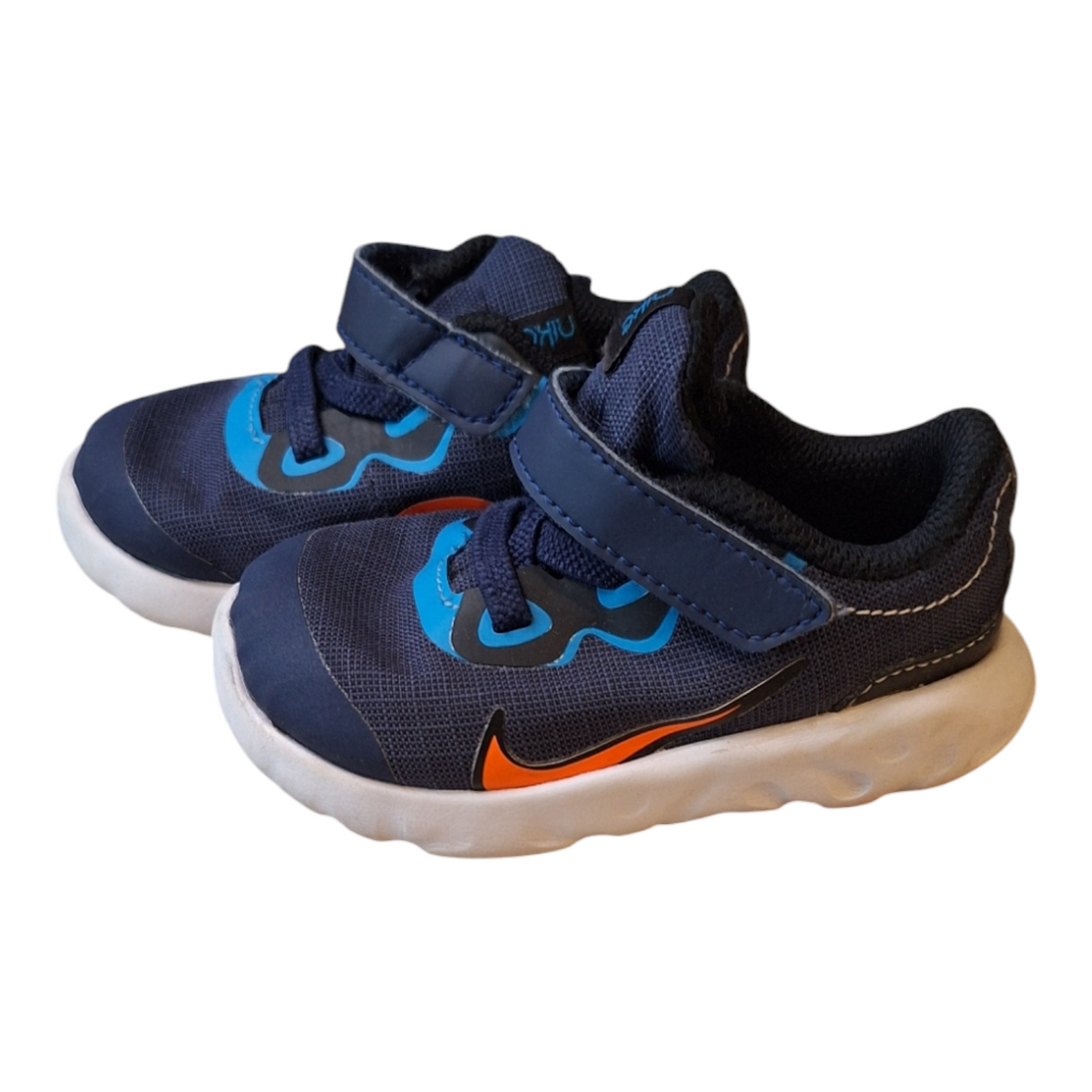A pair of Nike Explore Strada sneakers, size 21. The shoes are navy fabric with orange and blue accents, a strap closure, and a white rubber sole.